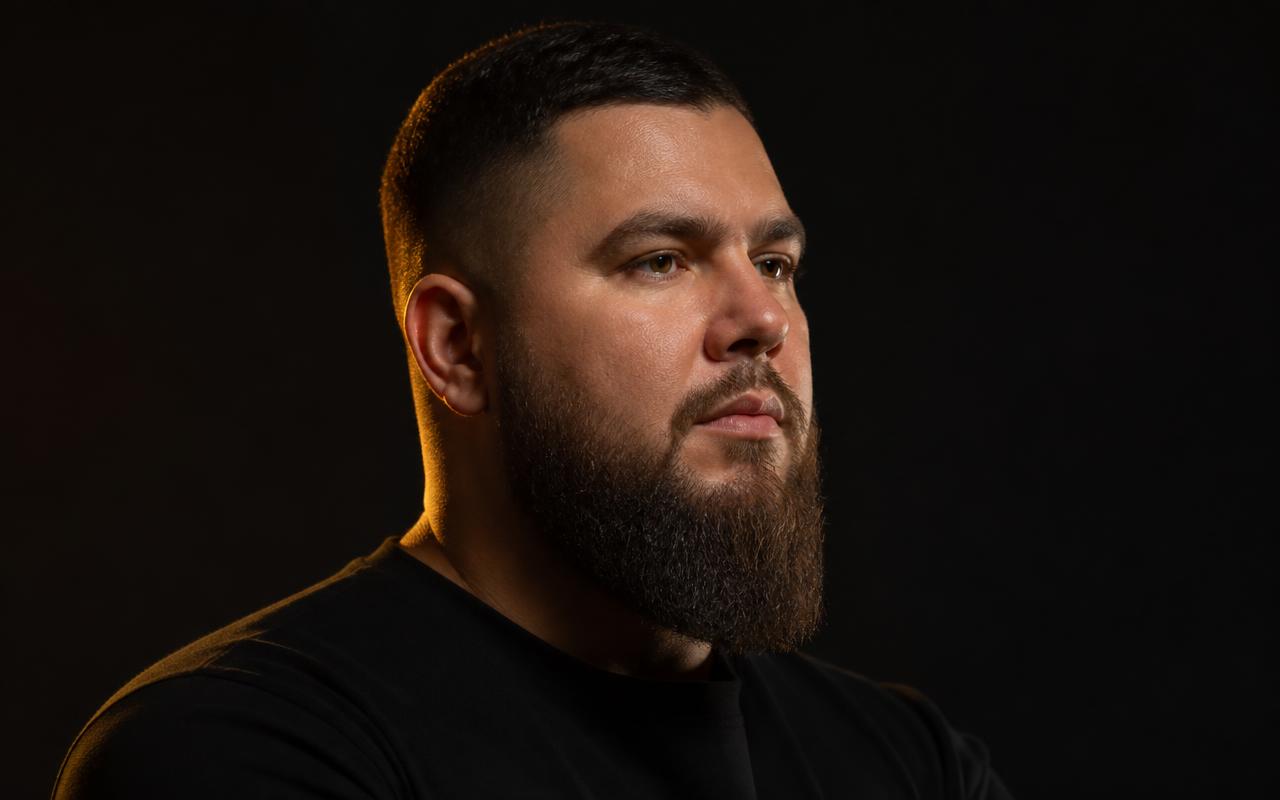 Bearded man with a round face wearing a short tapered beard with length kept at the chin
